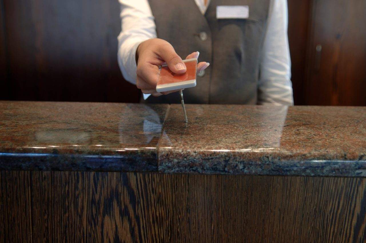 Person handing over a hotel key card across a reception desk