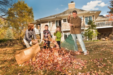 Family raking autumn leaves in the yard to get rid of Fall Pests