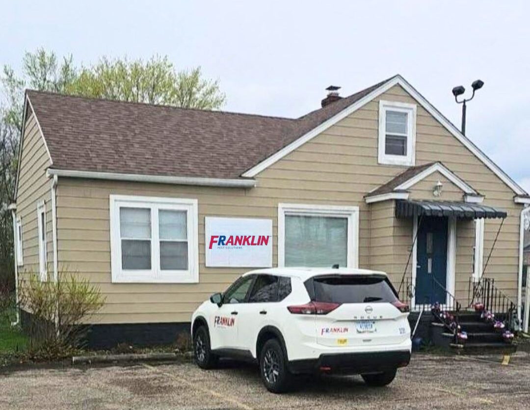 A beige single-story house with a sloped roof, a "Franklin" sign in the window, and a white SUV labeled "Franklin South Bend Pest Control Services" parked in front.