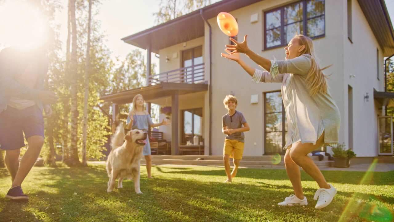 Family playing with a dog in the backyard lawn<br />
