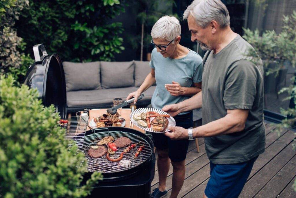 People grilling food outdoors on patio barbecue, sharing casual backyard cooking moment